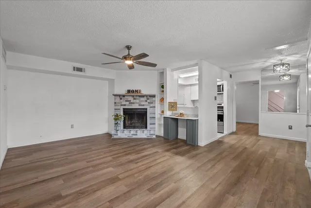 a view of a livingroom with a fireplace a sink and dishwasher with wooden floor