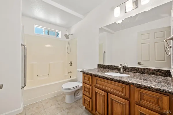 a bathroom with a granite countertop sink a toilet and shower