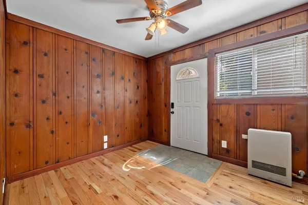 a view of empty room with wooden floor and fan