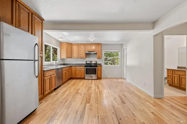 a kitchen with a refrigerator a stove top oven a wooden floor and a window