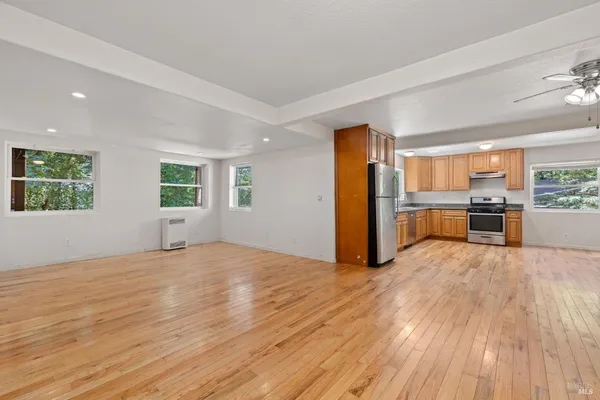 a view of an empty room with window and wooden floor