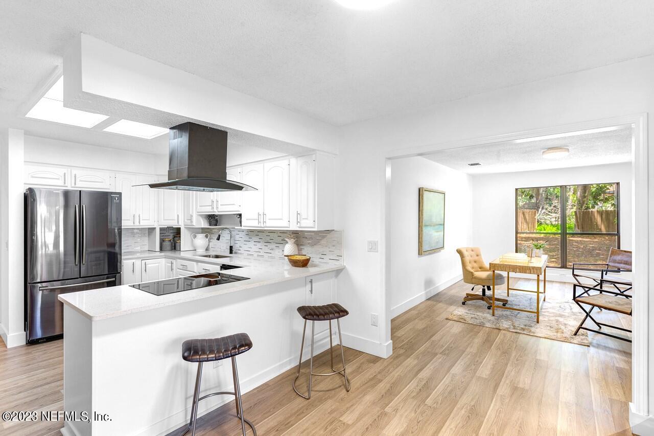 4309 Monument Road Jacksonville, FL 32225 - Photo 27 of 65 a kitchen with a refrigerator a stove a dining table and chairs with wooden floor