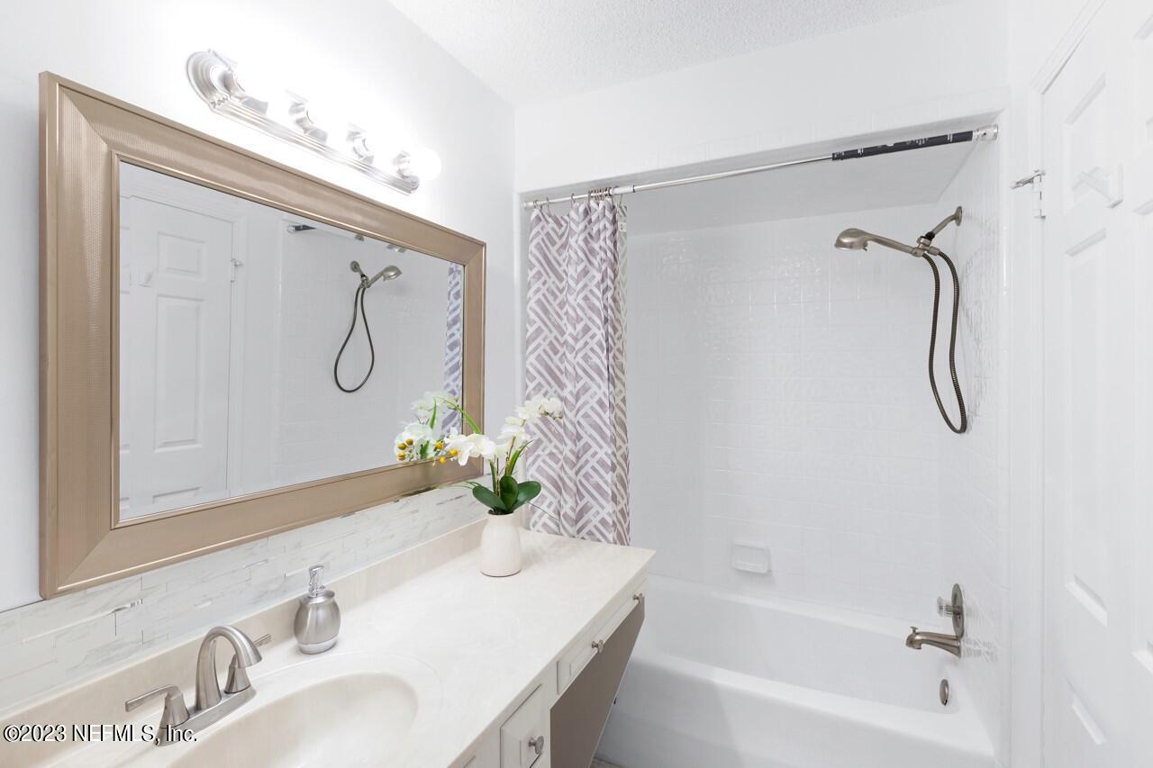 4309 Monument Road Jacksonville, FL 32225 - Photo 49 of 65 a bathroom with a granite countertop sink a mirror and a shower