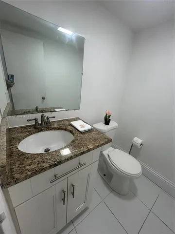 a bathroom with a granite countertop sink a toilet and a mirror
