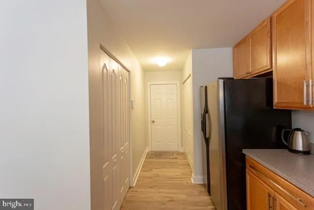 a view of a refrigerator in kitchen and an empty room