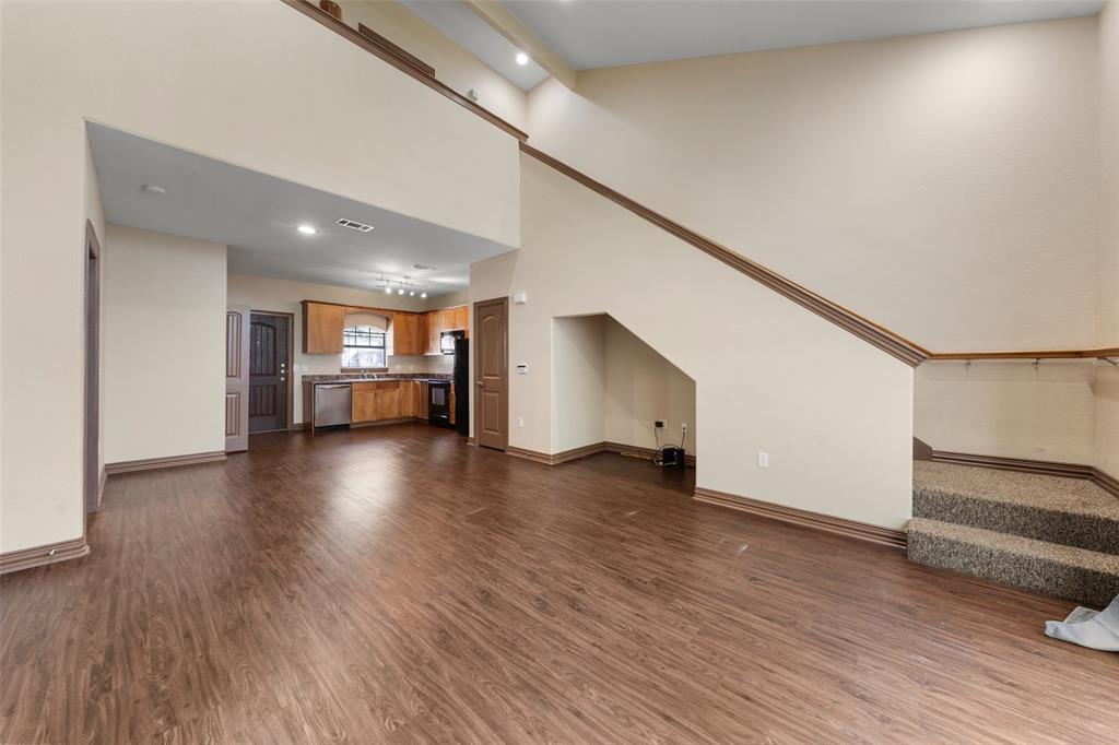 2410 South 2nd Street, Unit 1053 Waco, TX 76706 - Photo 4 of 27 Unfurnished living room with a towering ceiling, dark wood-style flooring, stairway, and recessed lighting