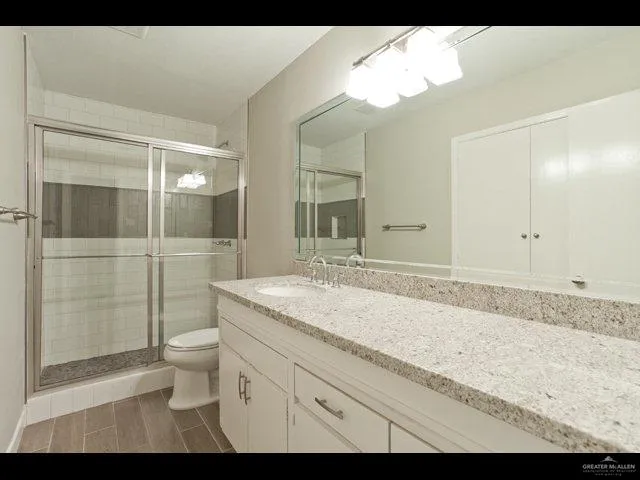 a bathroom with a granite countertop sink toilet and shower