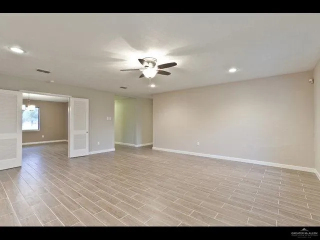 a view of an empty room with chandelier fan and fire place