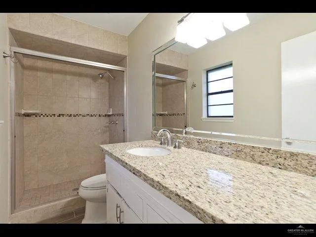 a bathroom with a granite countertop sink toilet and shower
