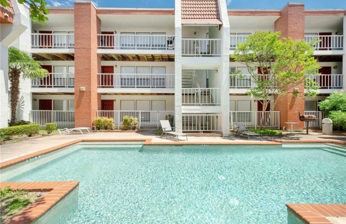 3115 Helms Street, Unit 111 Austin, TX 78705 - Photo 12 of 13 A refreshing swimming pool awaits residents, surrounded by lush green landscaping.