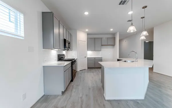 a large kitchen with kitchen island a sink dishwasher a stove and a refrigerator with wooden floor