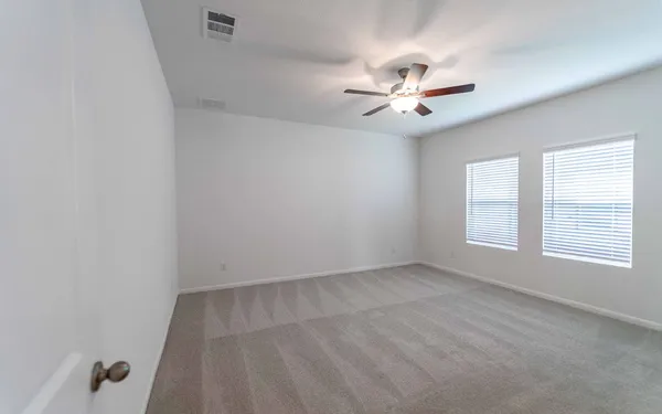 an empty room with windows and fan