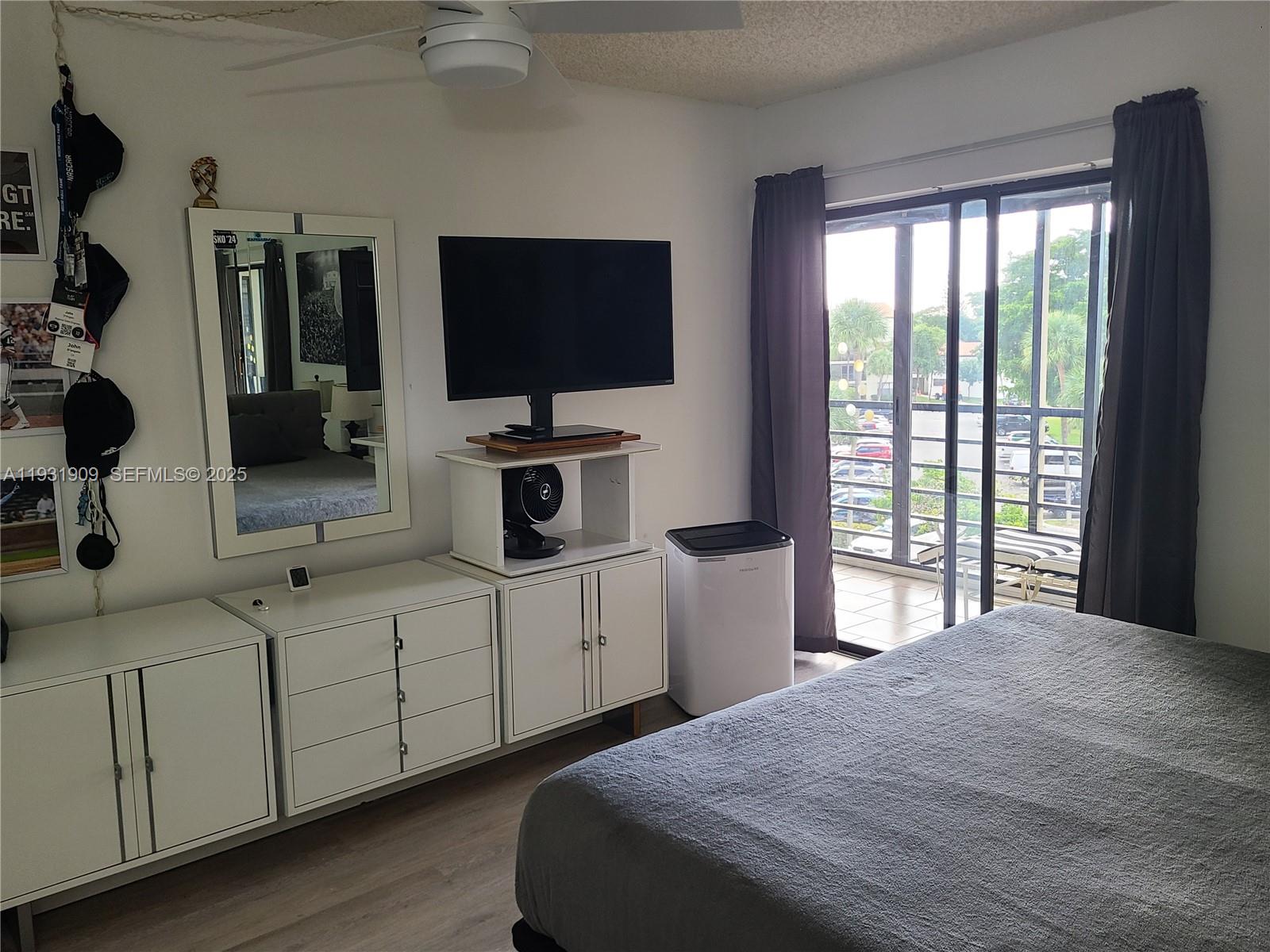 2306 South Cypress Bend Drive, Unit 418 Pompano Beach, FL 33069 - Photo 3 of 18 a bedroom with a bed and a flat tv screen on dresser