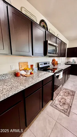 a kitchen with granite countertop a refrigerator and a stove top oven