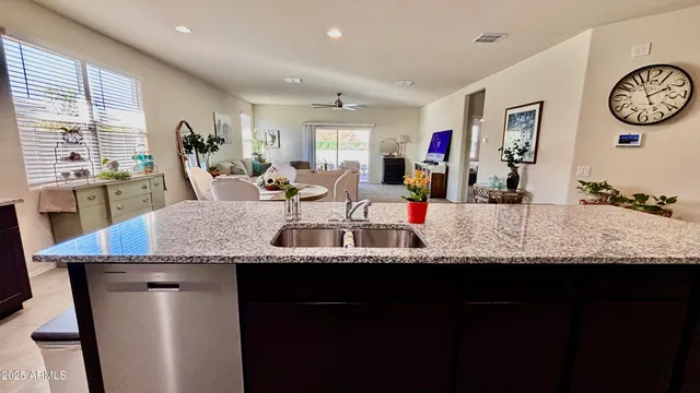 a kitchen with stainless steel appliances kitchen island granite countertop a sink counter top space and a view of living room