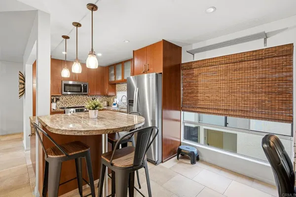 a kitchen with kitchen island a refrigerator table and chairs