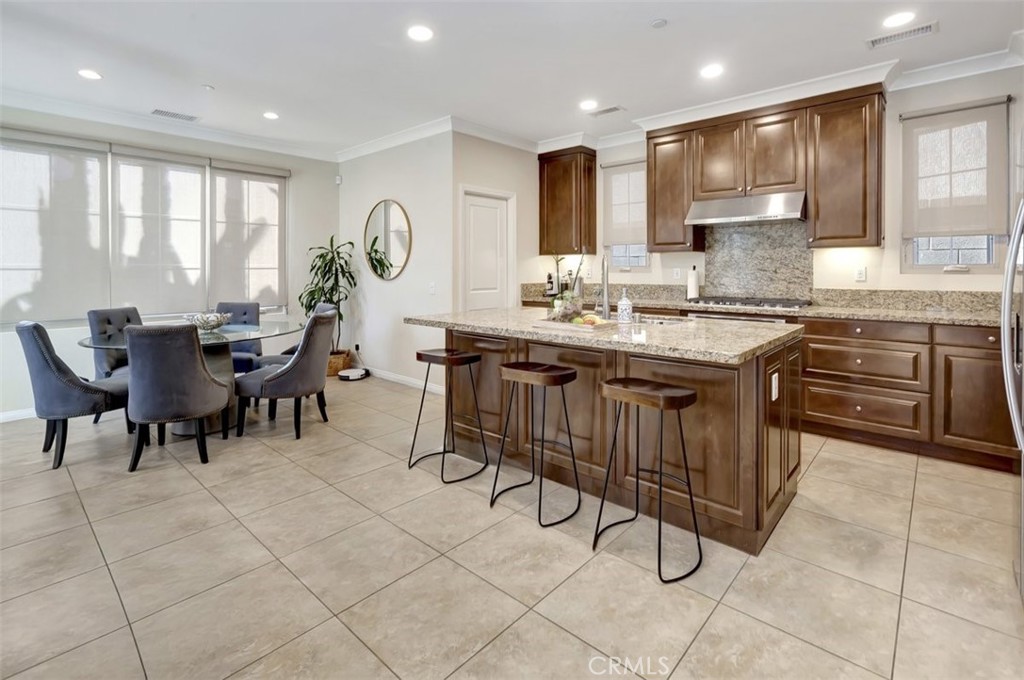 67 Hanging Garden Irvine, CA 92620 - Photo 7 of 23 a kitchen with kitchen island granite countertop wooden cabinets a dining table and chairs