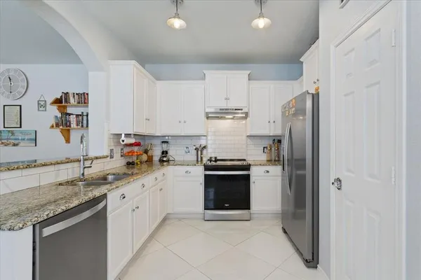a kitchen with stainless steel appliances granite countertop a refrigerator sink and white cabinets