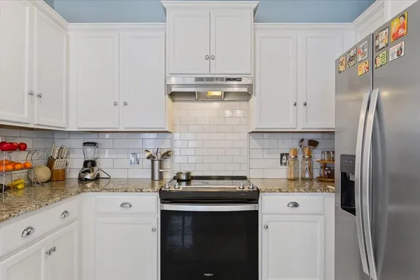 a kitchen with stainless steel appliances granite countertop a refrigerator sink and white cabinets