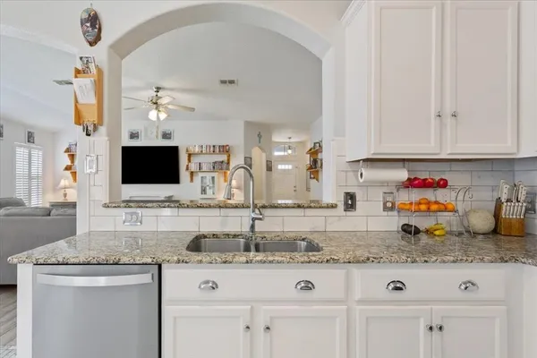 a kitchen with granite countertop a sink and white cabinets