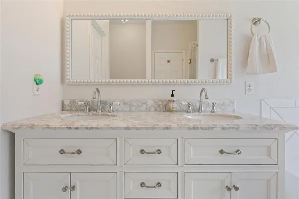 a bathroom with a granite countertop sink and white cabinets
