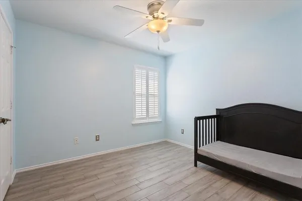 a view of a bedroom with wooden floor and a ceiling fan