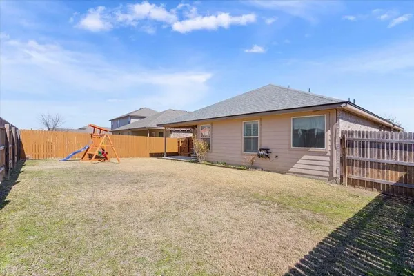 a view of a house with a yard and wooden fence