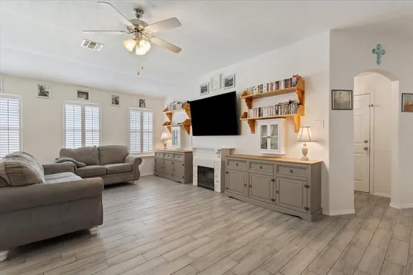 a living room with furniture flat screen tv and a ceiling fan