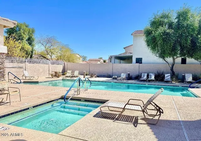 a view of swimming pool with lawn chairs under an umbrella