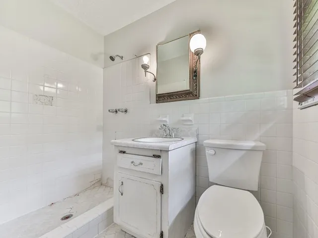 a bathroom with a toilet a sink a mirror and a window