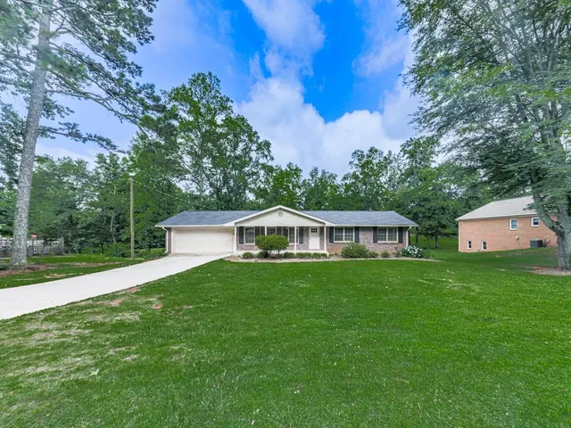 a front view of house with yard and trees all around