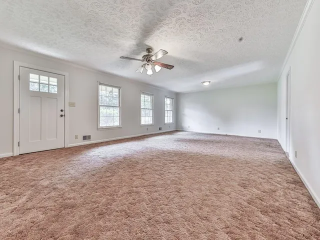 an empty room with windows and ceiling fan
