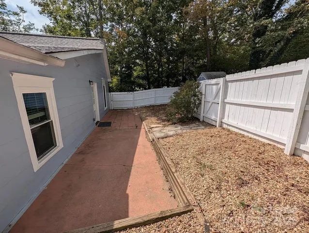 a view of backyard with small space and wooden fence