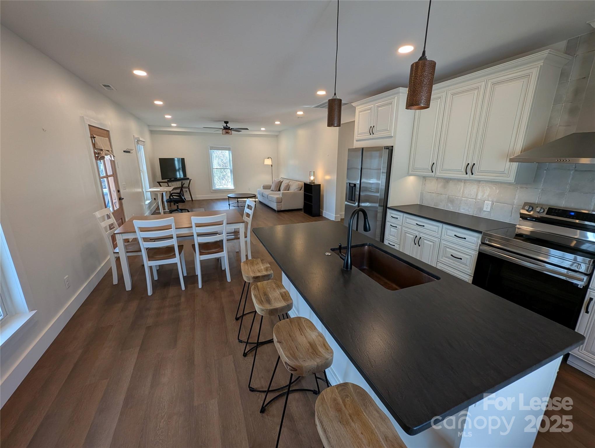 24 Woodrow Avenue Asheville, NC 28801 - Photo 7 of 30 a kitchen with stainless steel appliances granite countertop a refrigerator a stove a sink a dining table and chairs with wooden floor
