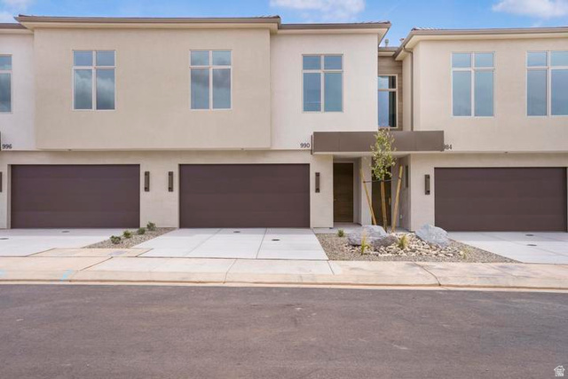 990 Manen Street Washington, UT 84780 - Photo 42 of 43 Modern townhome exterior featuring contemporary architecture, light-colored stucco facade, large multi-pane windows, and integrated two-car garage