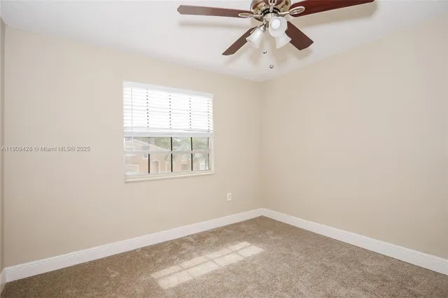 an empty room with a window and a fan