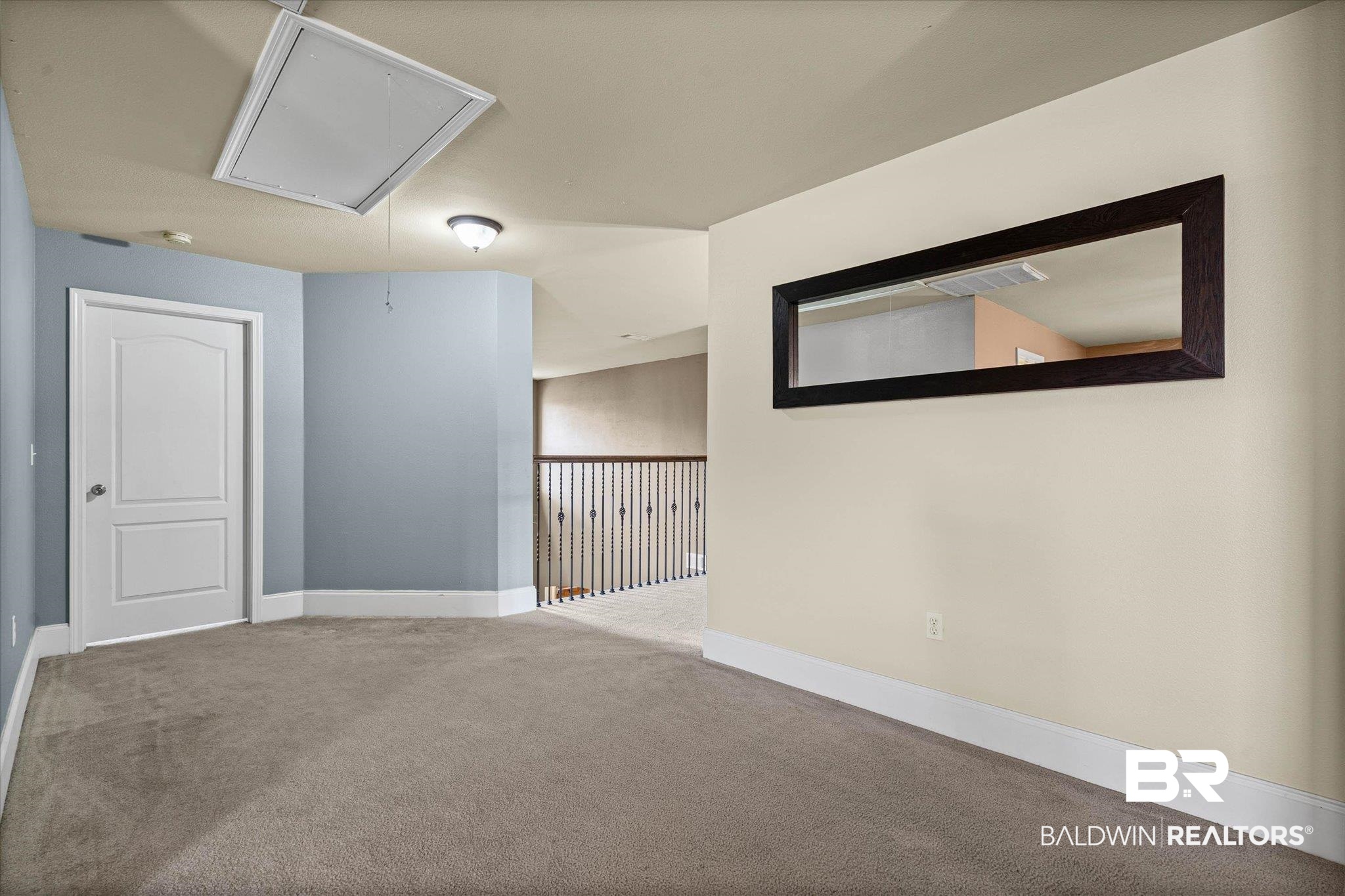 585 Sheffield Avenue Foley, AL 36535 - Photo 18 of 45 Carpeted space featuring a white paneled door, light blue and cream wall colors, white baseboards, and a dark wood-framed mirror