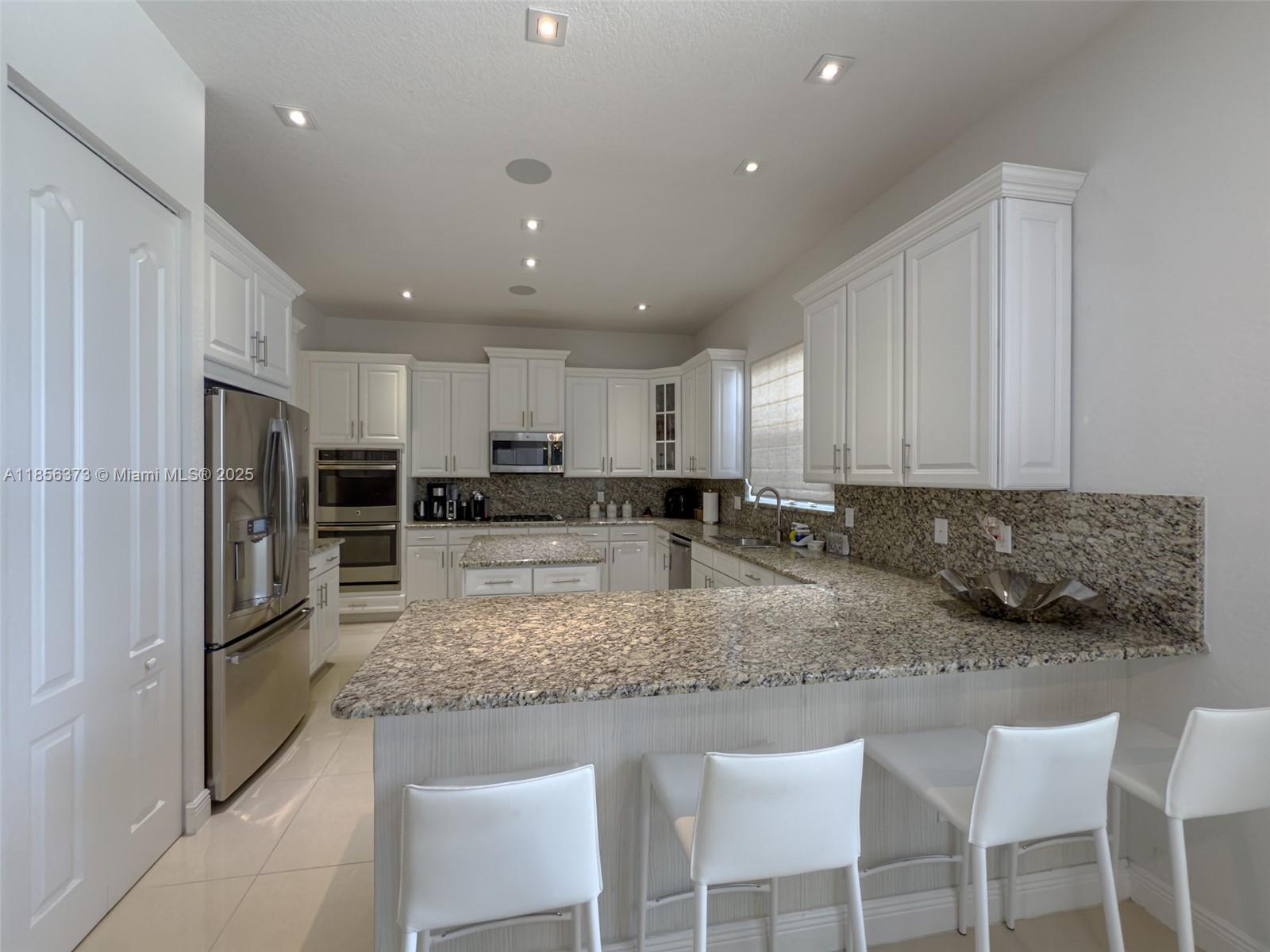 9709 Blue Isle Bay Parkland, FL 33076 - Photo 16 of 75 a kitchen with stainless steel appliances granite countertop a sink refrigerator and cabinets
