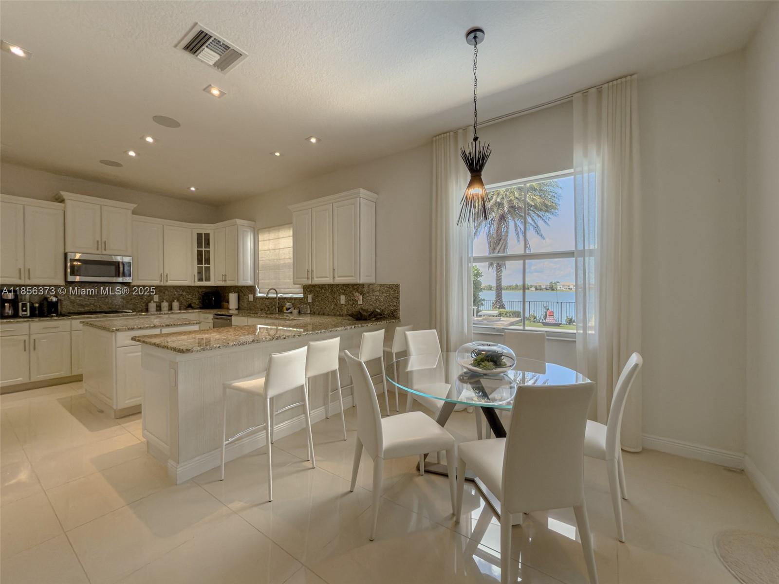 9709 Blue Isle Bay Parkland, FL 33076 - Photo 18 of 75 a kitchen with stainless steel appliances granite countertop a refrigerator a sink a stove a dining table and chairs