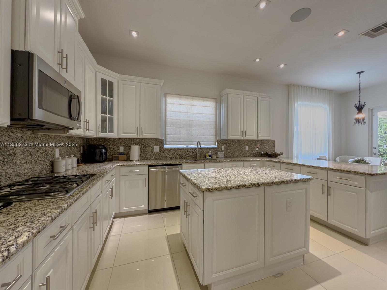 9709 Blue Isle Bay Parkland, FL 33076 - Photo 19 of 75 a kitchen with granite countertop a sink and cabinets