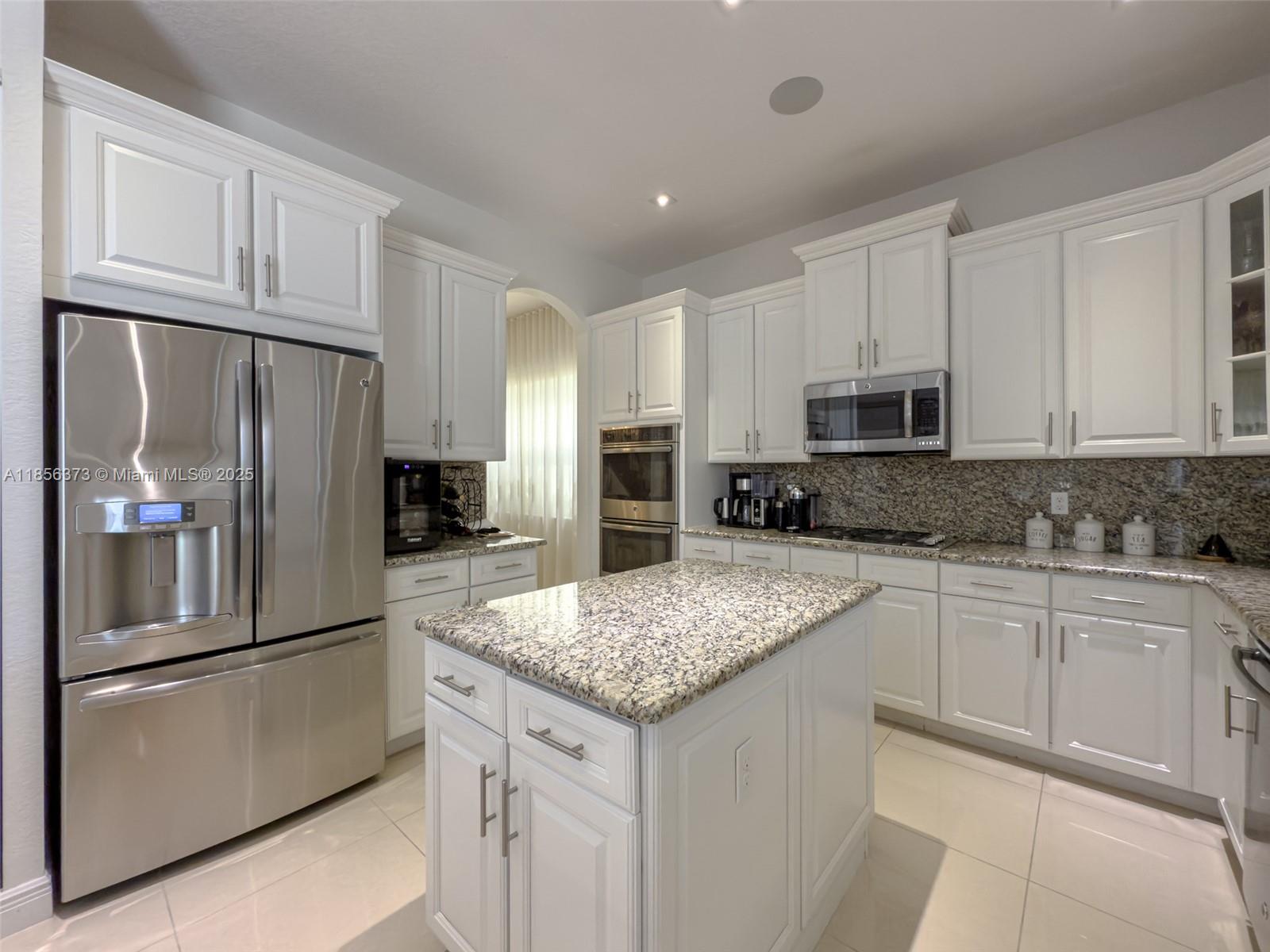 9709 Blue Isle Bay Parkland, FL 33076 - Photo 20 of 75 a kitchen with stainless steel appliances granite countertop a refrigerator a stove a sink and white cabinets