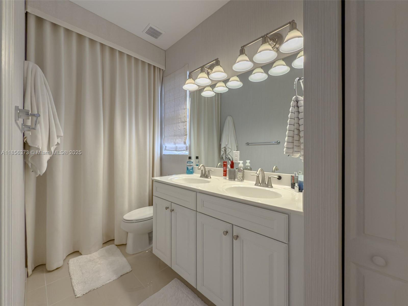 9709 Blue Isle Bay Parkland, FL 33076 - Photo 38 of 75 a bathroom with a toilet sink and mirror