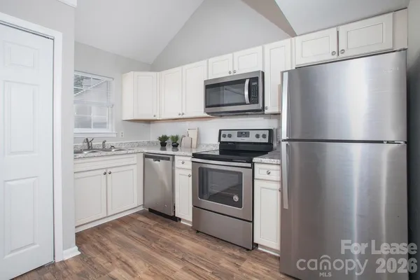 a kitchen with a refrigerator stove and white cabinets