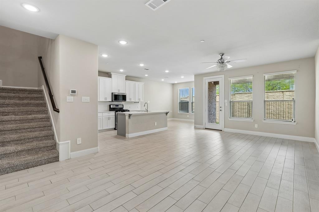 525 Teton Street Allen, TX 75002 - Photo 5 of 31 a view of an empty room with wooden floor and a kitchen