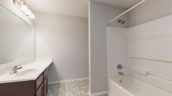 a bathroom with a tub sink vanity and mirror