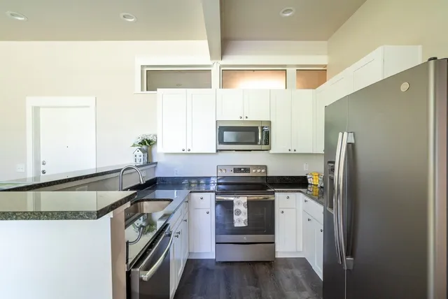 a kitchen with stainless steel appliances granite countertop a stove a sink and a refrigerator