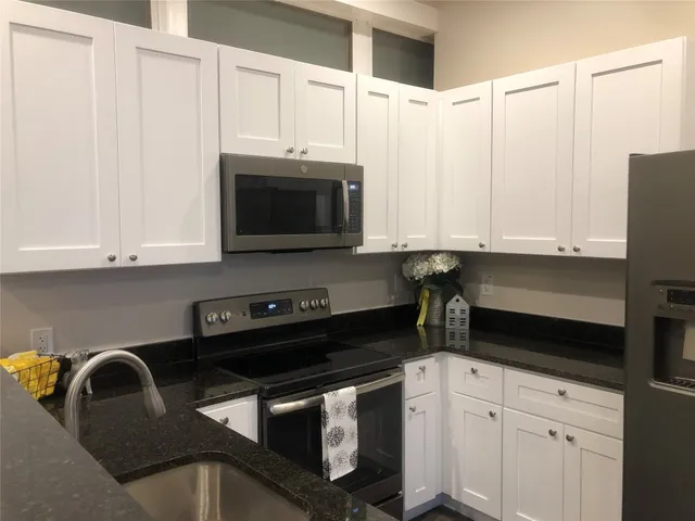 a kitchen with stainless steel appliances granite countertop a sink a stove a microwave and cabinets