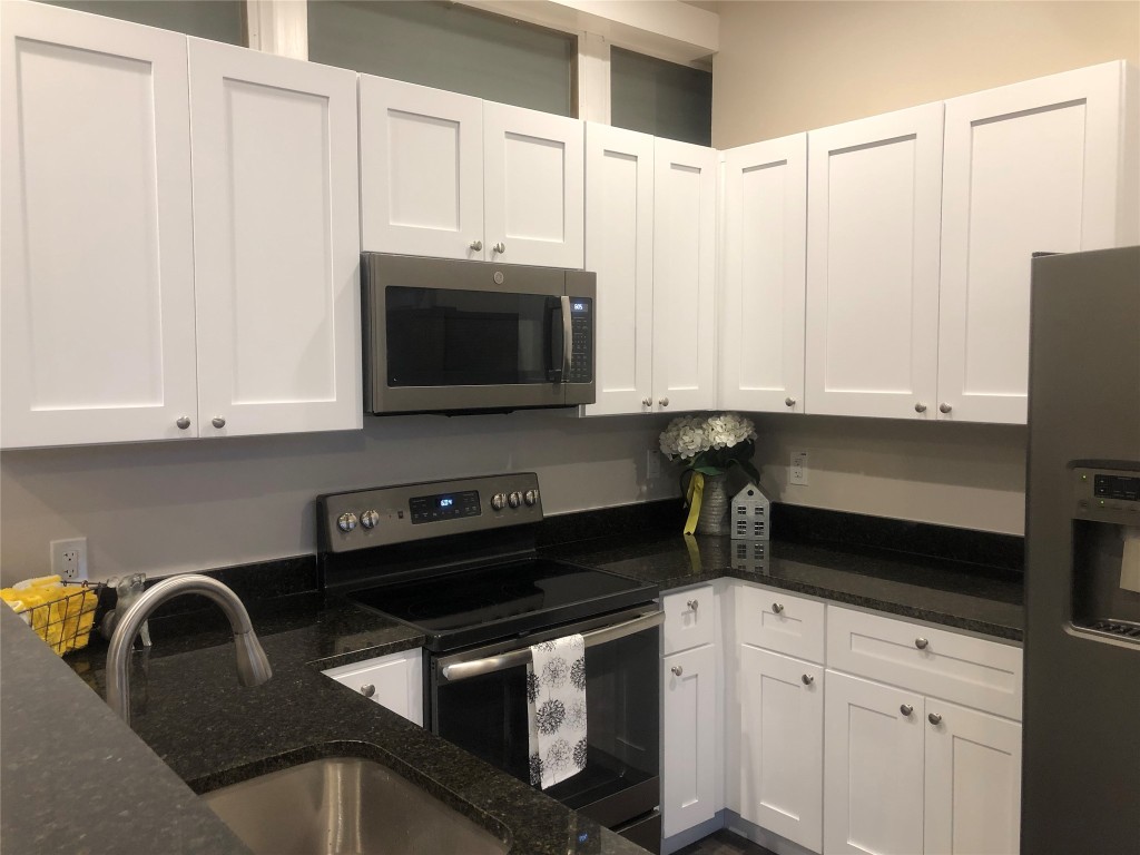 809 Vance Street Taylor, TX 76574 - Photo 3 of 10 a kitchen with stainless steel appliances granite countertop a sink a stove a microwave and cabinets