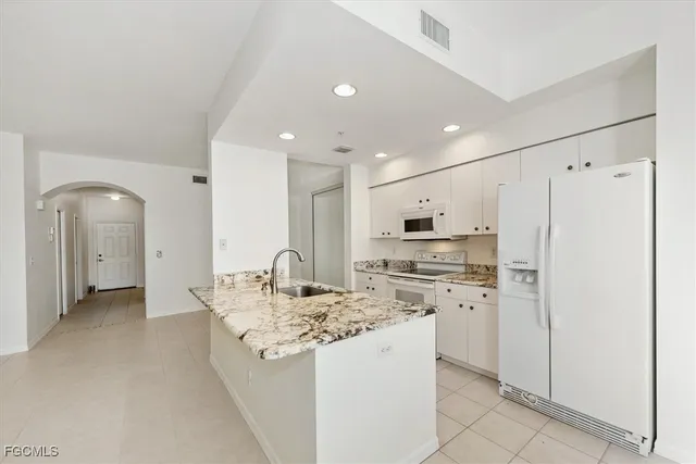 a kitchen with stainless steel appliances kitchen island granite countertop a refrigerator and a stove top oven