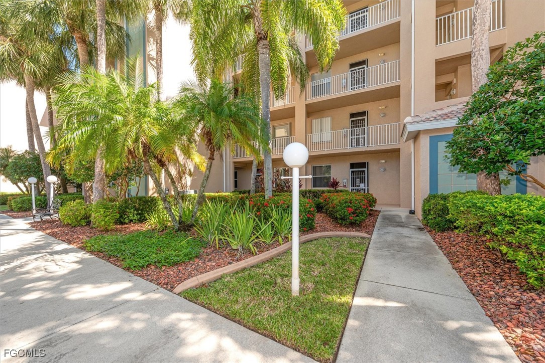 14111 Brant Point Circle, Unit 2106 Fort Myers, FL 33919 - Photo 2 of 31 a view of a brick house with a yard plants and palm trees
